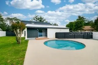Rear exterior view of the home featuring a private pool, expansive patio, and fenced backyard.