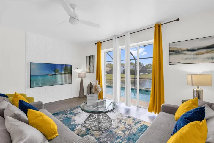 Light-filled living room with expansive sliding doors showcasing beautiful pool and lake views, complemented by modern finishes and an inviting layout