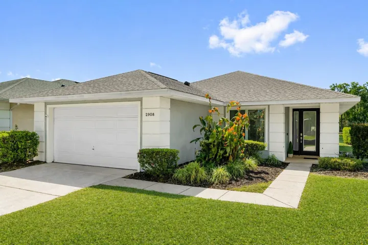 Front exterior with walkway entry and mature landscaping in Kissimmee community