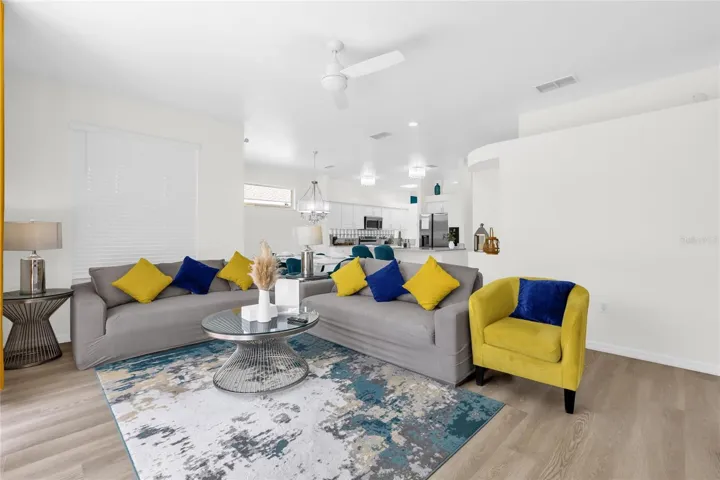 Spacious open-concept living room with modern furnishings, abundant natural light, and seamless flow into the kitchen and dining areas