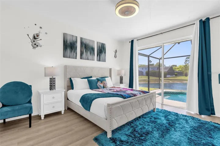 Spacious primary bedroom featuring serene lake and pool views, large sliding glass doors, abundant natural light, and elegant finishes for a relaxing retreat