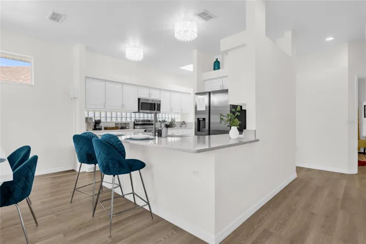 Open-concept kitchen with breakfast bar seating, quartz countertops, and modern finishes, seamlessly connecting to the main living space