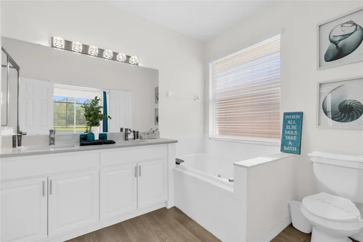 Spacious primary bathroom with dual vanity, soaking tub, and natural light