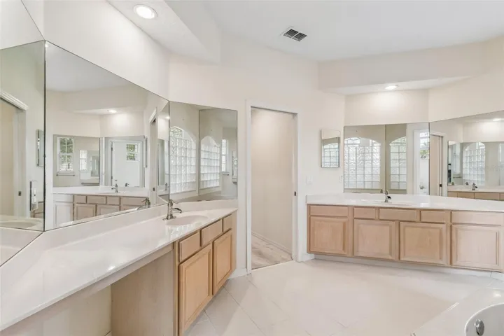 Primary suite overlooking the pool, featuring two closets and an ensuite bathroom with dual vanities, a walk-in shower, a garden tub, and a private water closet