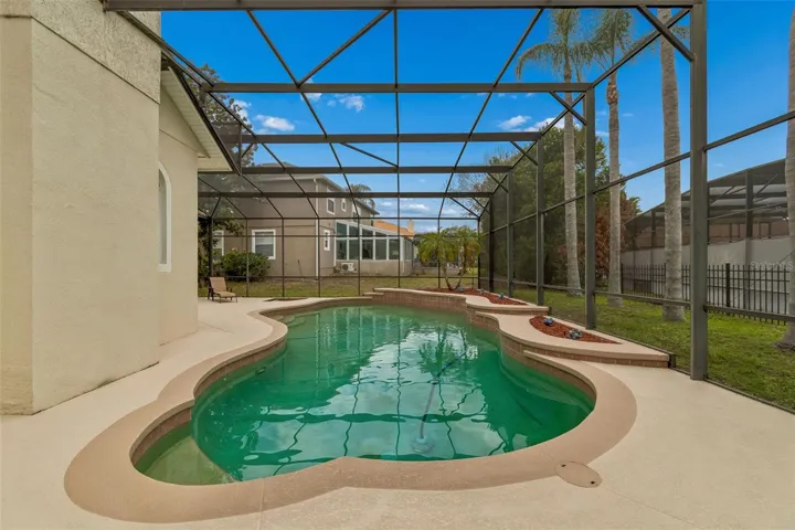 Spacious outdoor pool area featuring a 27’ x 9’ covered patio and a resort-style pool within a screened enclosure