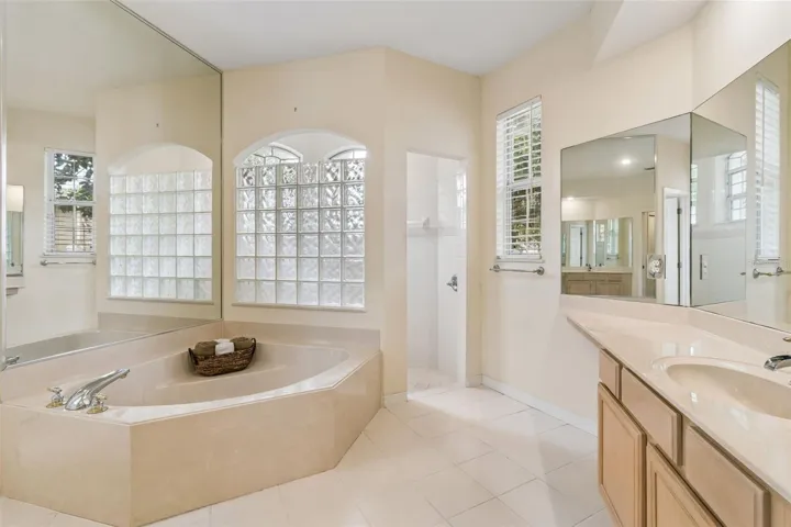 Primary suite overlooking the pool, featuring two closets and an ensuite bathroom with dual vanities, a walk-in shower, a garden tub, and a private water closet