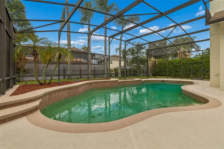Spacious outdoor pool area featuring a 27’ x 9’ covered patio and a resort-style pool within a screened enclosure