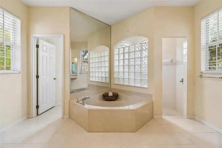 Primary suite overlooking the pool, featuring two closets and an ensuite bathroom with dual vanities, a walk-in shower, a garden tub, and a private water closet