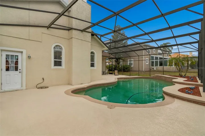 Spacious outdoor pool area featuring a 27’ x 9’ covered patio and a resort-style pool within a screened enclosure