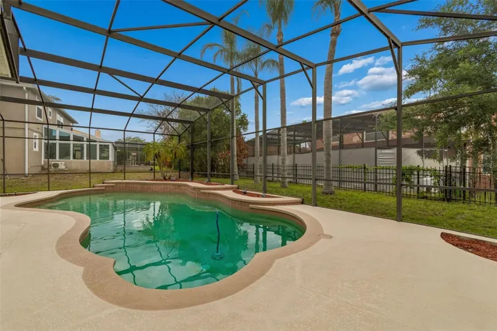 Spacious outdoor pool area featuring a 27’ x 9’ covered patio and a resort-style pool within a screened enclosure