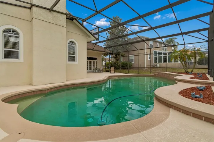Spacious outdoor pool area featuring a 27’ x 9’ covered patio and a resort-style pool within a screened enclosure