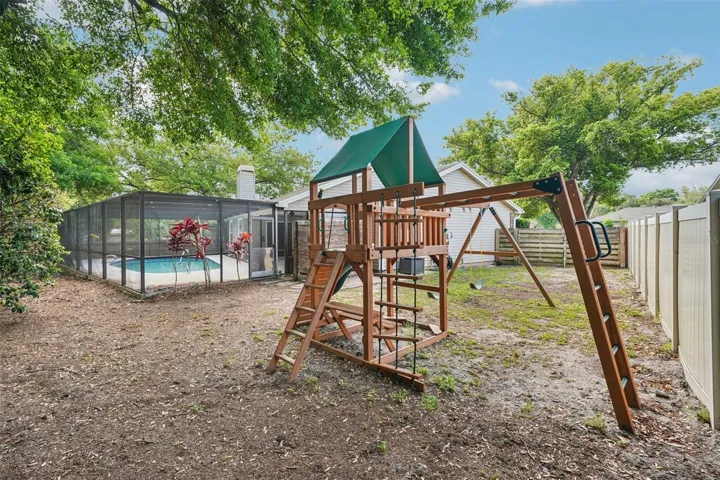 The expansive, fully fenced backyard features an enclosed outdoor shower area just off the pool with a rain shower head and handheld nozzle, while the side yards offer plenty of space to roam or garden, a playset, a swing under the mature oak, and a fire pit to gather around on cooler evenings.