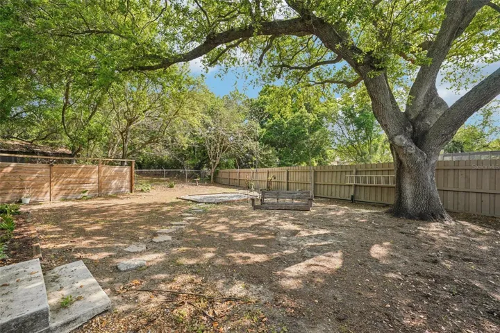 The expansive, fully fenced backyard features an enclosed outdoor shower area just off the pool with a rain shower head and handheld nozzle, while the side yards offer plenty of space to roam or garden, a playset, a swing under the mature oak, and a fire pit to gather around on cooler evenings.