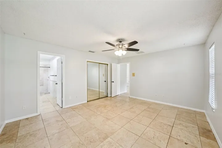 The primary suite boasts travertine flooring, an oversized walk-in closet, and an en-suite bathroom with a walk-in shower surrounded by beautiful travertine tile, and a brand-new dual-sink vanity.