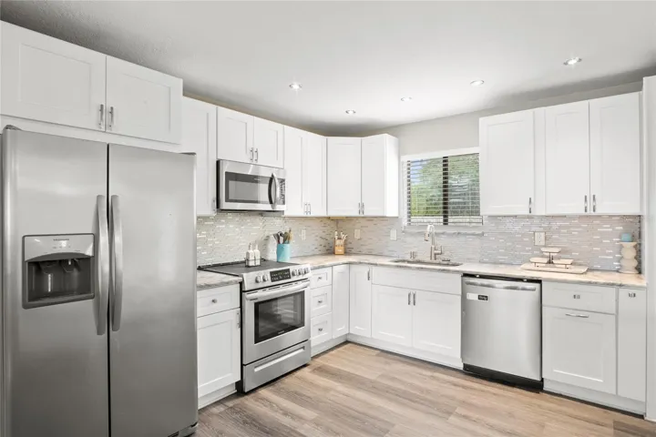 A modern kitchen with stainless steel appliances and a beautiful backsplash.