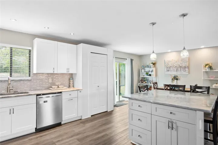 A view of the kitchen, island, and dining room looking out to the fenced-in back yard.