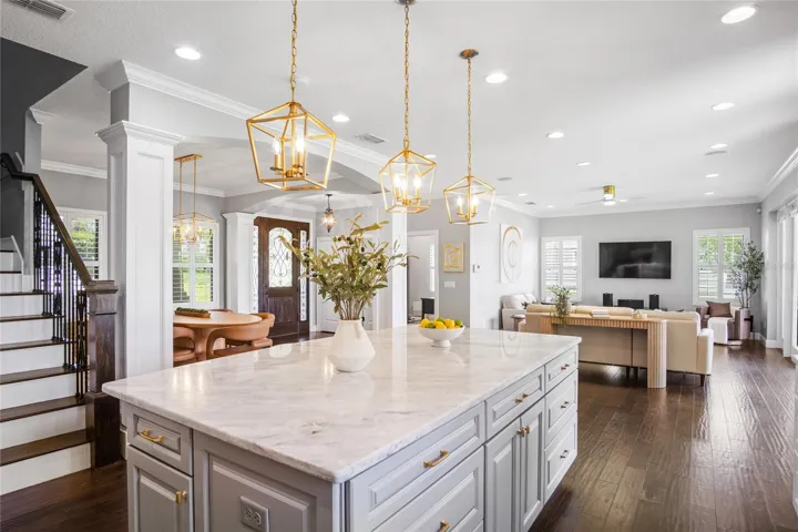 The view of the downstairs stretching from the staircase and sweeping across to the dining area, front door, office, living room, and kitchen.