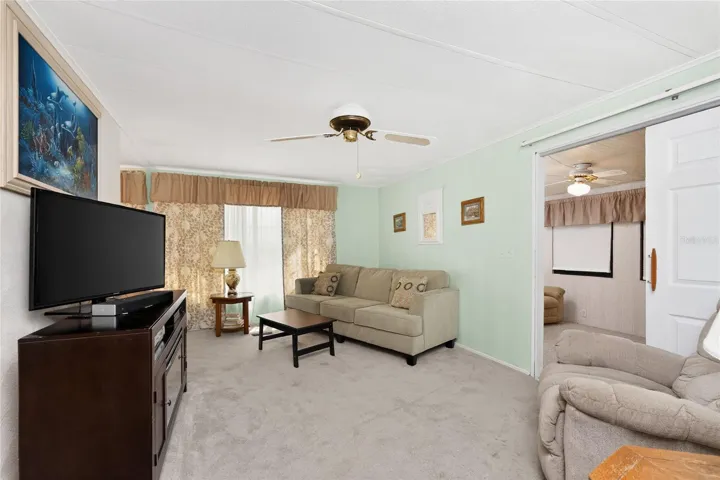 Living room features carpeted flooring and ceiling fan
