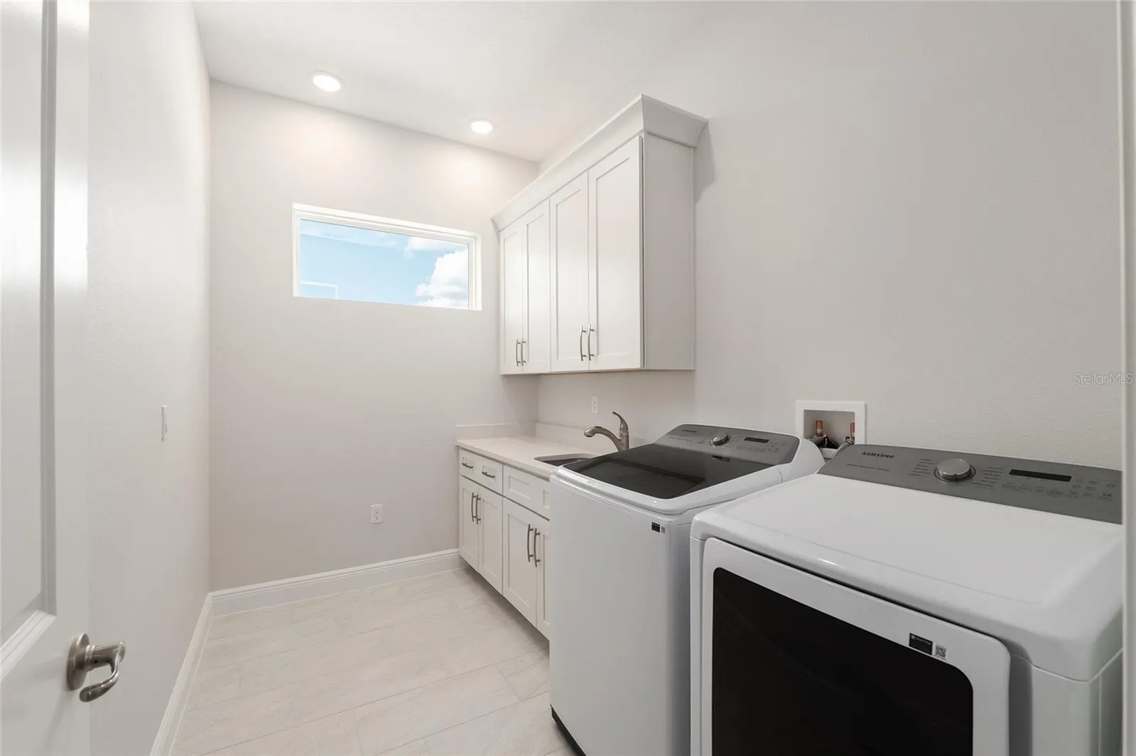 Laundry room with utility sink, cabinetry, and more natural light!