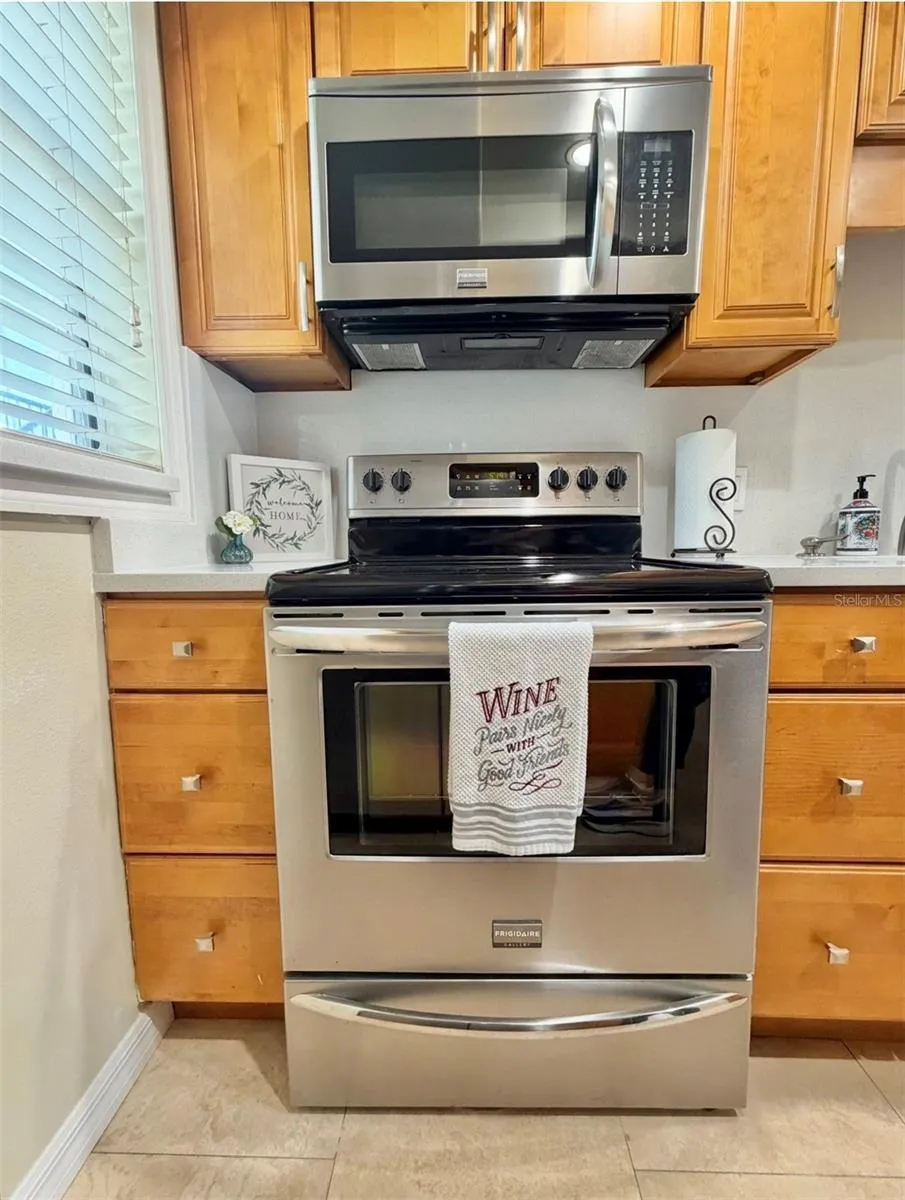 Stainless appliances and a view out the window to the front porch.