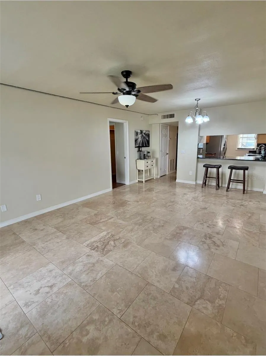The living room is 20x12 and features travertine floors and a newer fan and light fixture.