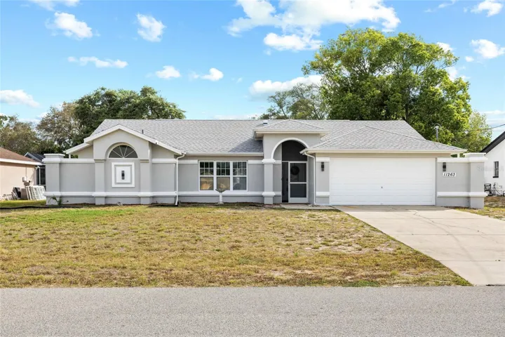 Curbside view of the stunning 3/2, 2 car garage CBH pool home with fresh paint inside, new roof 2025, remodeled kitchen, bathrooms, laundry room, all new ceiling fans, and so much more!