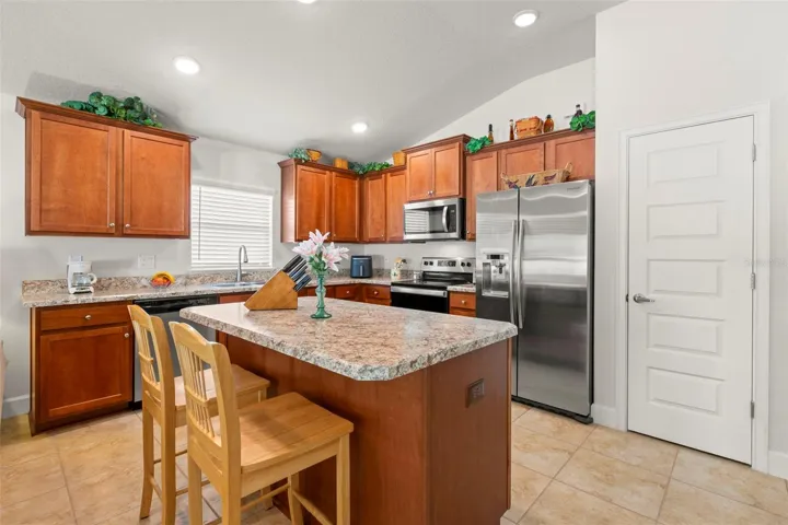An oversized center island anchors the kitchen, offering additional prep space, breakfast bar seating, and a natural gathering point within the heart of the home.