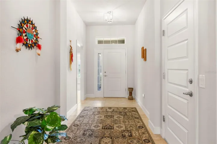 A dramatic entry foyer creates an impressive first impression, featuring elevated ceiling height, transom window detailing, and 18” tile flooring.