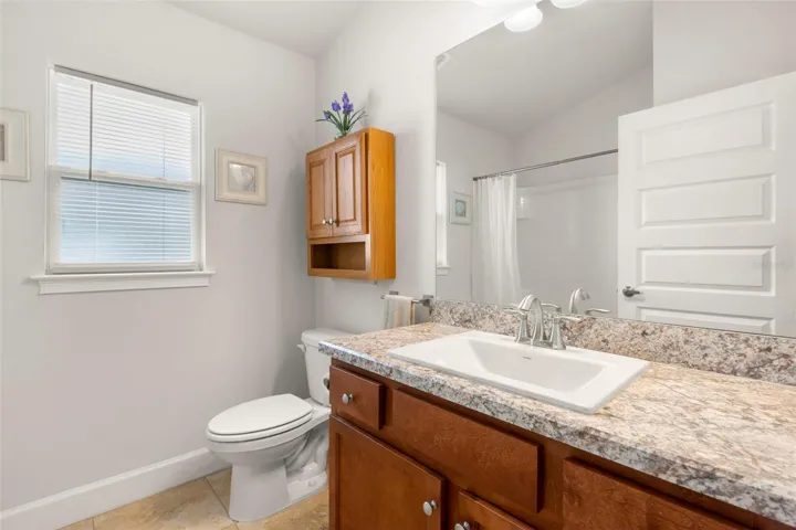The secondary bathroom is thoughtfully appointed with an extended vanity, ample counter space, and a full tub/shower combination—ideal for guests or family use with a privacy window that fills the space with natural light.