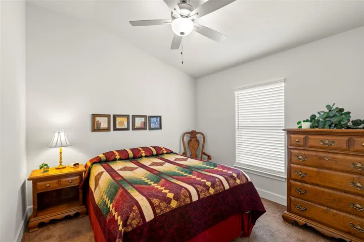 Bedroom 3 is bright and comfortable with neutral finishes, plush carpeting, a ceiling fan, and a generously sized window for natural light.