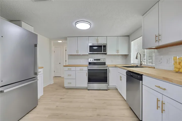 KITCHEN WITH GOLD HARDWARE AND LUXURY VINYL PLANK FLOORS.
