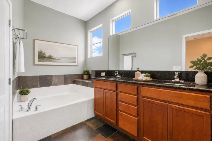 Spacious primary ensuite featuring dual vanities, a soaking tub, separate glass-enclosed shower, and abundant natural light