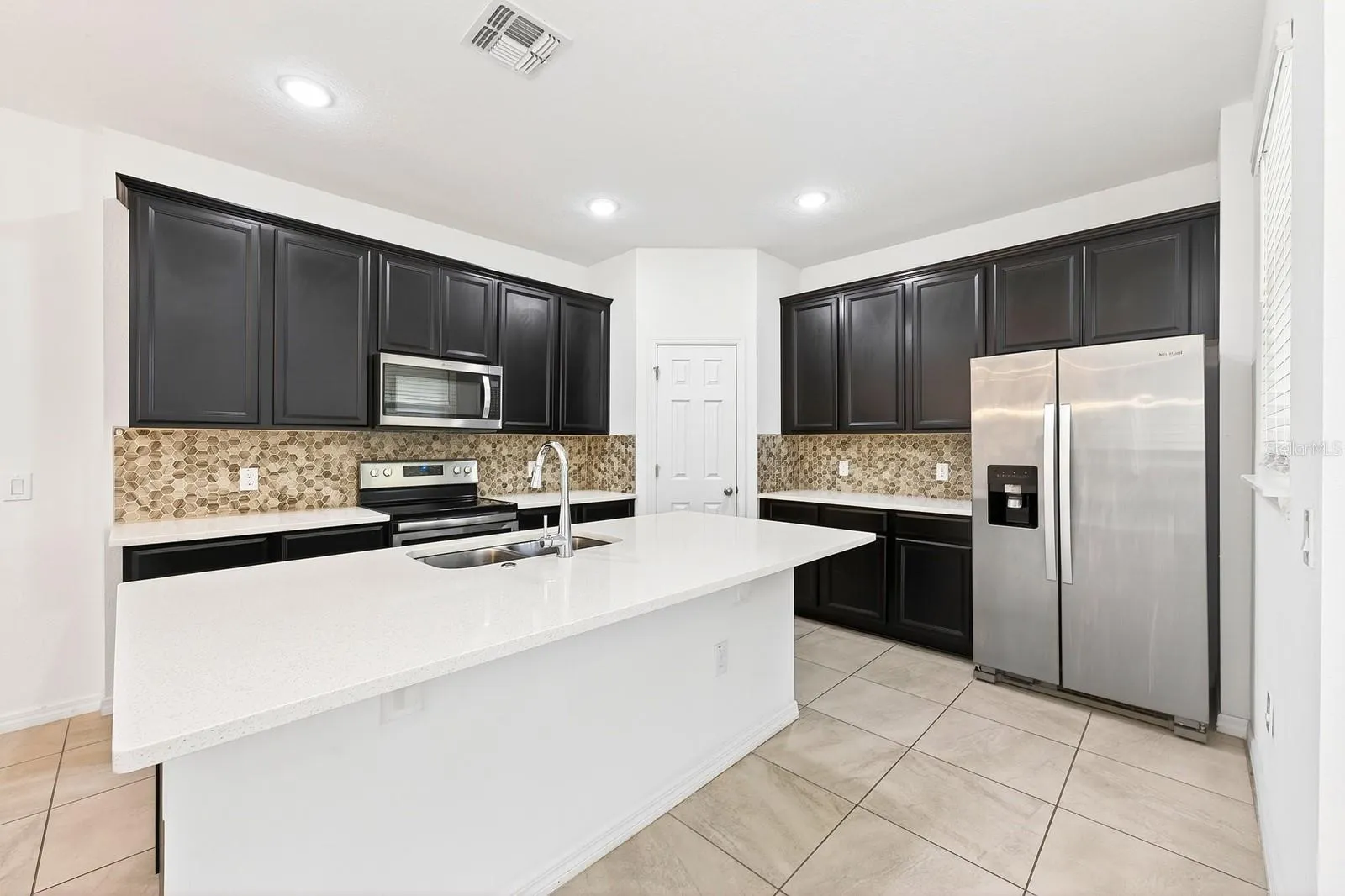 The comfortable open kitchen is the heart of the home featuring rich solid wood cabinetry, STAINLESS STEEL APPLIANCES, pantry storage, a stylish backsplash and a large contrasting ISLAND with casual bar seating overlooking the living and dining areas.