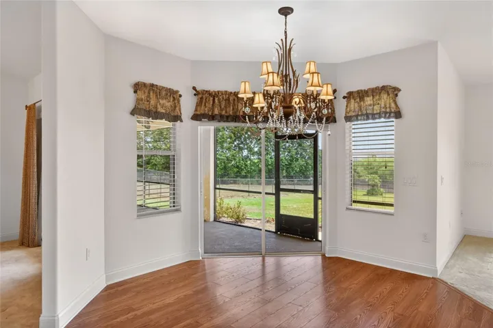 The dinette, family room, and kitchen come together as one open space, with another set of doors leading out to the lanai as sunlight fills the room.