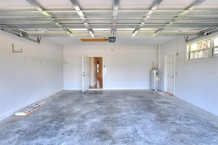 The garage opens into a hallway that leads toward the laundry room, kitchen, and main hall, with light guiding you back through the home.
