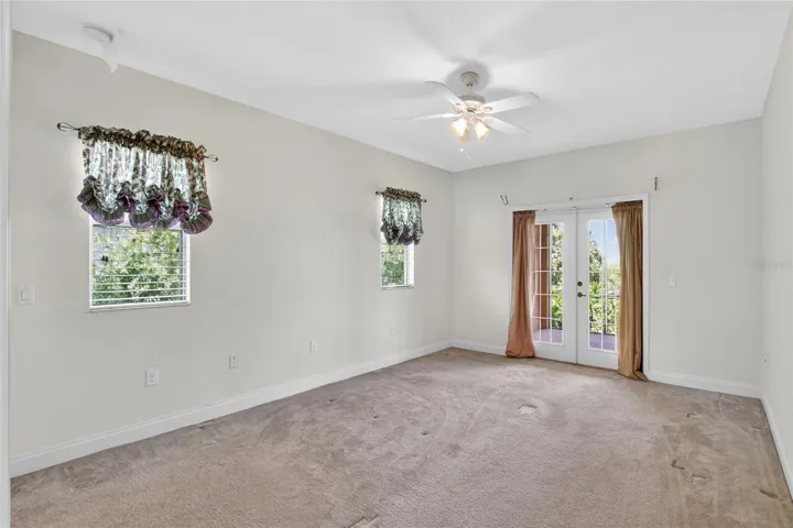French doors from the primary suite open to the lanai, letting in soft light and another quiet look toward the lake.