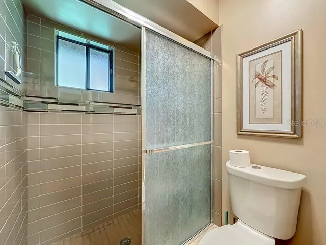 Primary Bathroom Extended single vanity -full wall mirror-Walk in tile shower-with window and glass enclosure