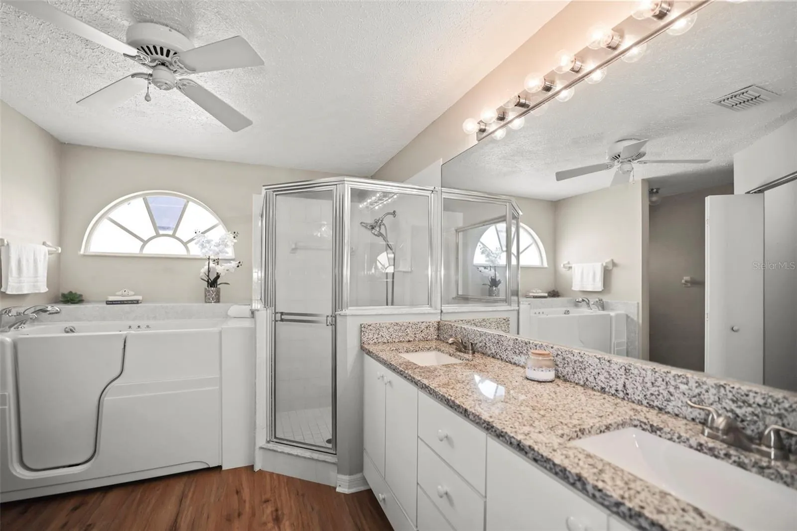 En-suite bath with double sink vanity, separate shower, and soak tub