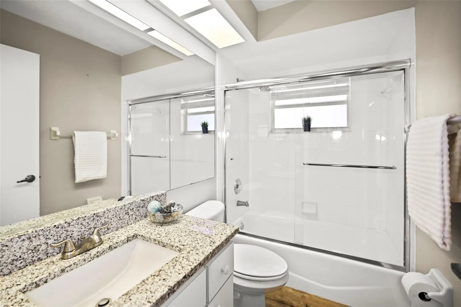 Guest Bath with bathtub, granite countertop and window allowing natural light.