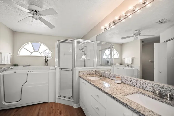 En-suite bath with double sink vanity, separate shower, and soak tub