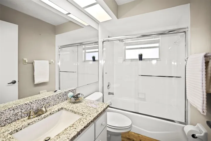 Guest Bath with bathtub, granite countertop and window allowing natural light.