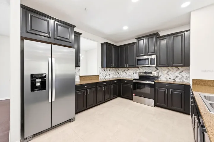 The Kitchen is well-appointed with 42” cabinetry, STONE COUNTERTOPS, stainless steel appliances, a tile backsplash, a pantry closet, and a breakfast bar.