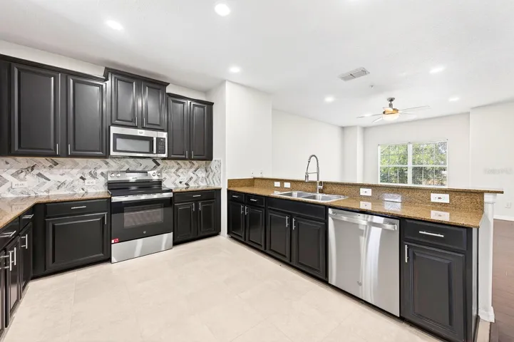 The Kitchen is well-appointed with 42” cabinetry, STONE COUNTERTOPS, stainless steel appliances, a tile backsplash, a pantry closet, and a breakfast bar.