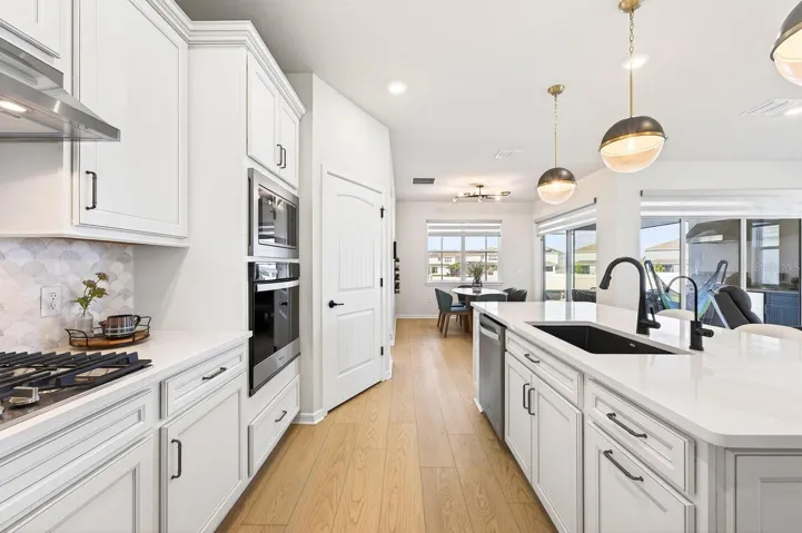 The Kitchen is a TRUE SHOWPIECE, thoughtfully designed with white cabinetry, stone countertops, a stylish tile backsplash, stainless steel appliances, BUILT-IN OVENS, a gas cooktop, a closet pantry, and an oversized breakfast bar that anchors the space beautifully.