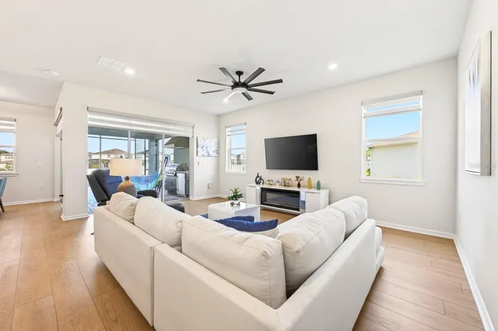 NATURAL LIGHT pours into the main living spaces through large windows with ELECTRIC BLINDS and dramatic corner sliding glass doors, creating a seamless transition to the outdoor living area.