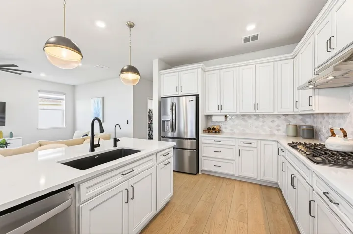 The Kitchen is a TRUE SHOWPIECE, thoughtfully designed with white cabinetry, stone countertops, a stylish tile backsplash, stainless steel appliances, BUILT-IN OVENS, a gas cooktop, a closet pantry, and an oversized breakfast bar that anchors the space beautifully.