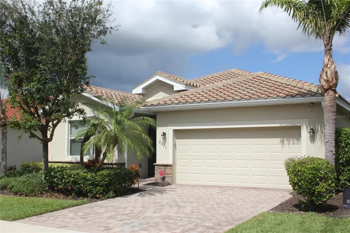 Contemporary Spanish-style home featuring stucco siding, decorative driveway, a tile roof, and an attached garage