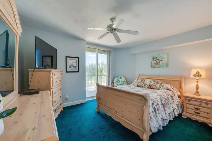 This inviting bedroom includes a ceiling fan, and sliding glass doors that provide natural light and access to a private balcony.
