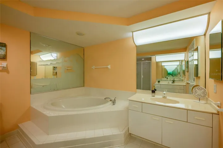 A second view highlights the oversized vanity and soaking tub, offering both functionality and comfort.