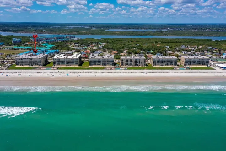 Stunning overhead view emphasizing the building’s direct beachfront location with expansive ocean vistas.